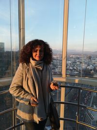 Portrait of woman standing in elevator with cityscape in background