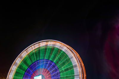 Illuminated ferris wheel against sky at night