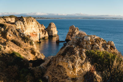 Rock formations by sea against sky