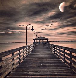 Pier over sea against sky during sunset