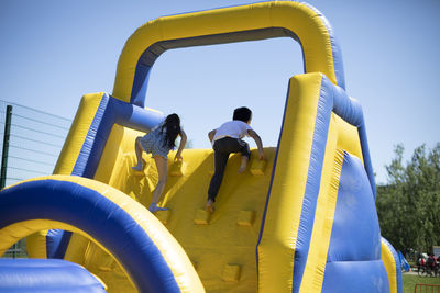 People in playground against clear blue sky