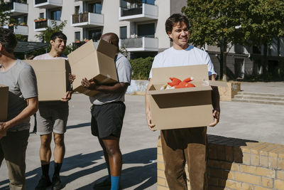 Multiracial group of volunteers holding cardboard boxes while working at community center