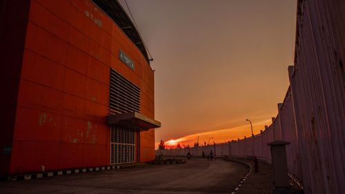 Street amidst buildings against sky at sunset