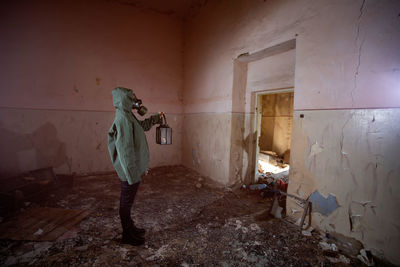 Woman holding oil lamp wearing gas mask standing amidst smoke