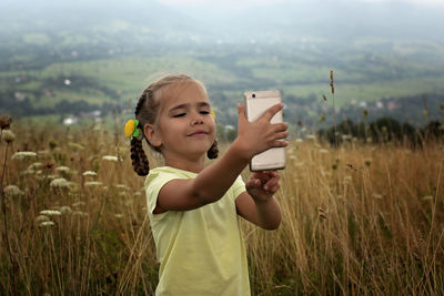 Cute 5-6 years old little girl sharing a photo on social media in internet in the mountains