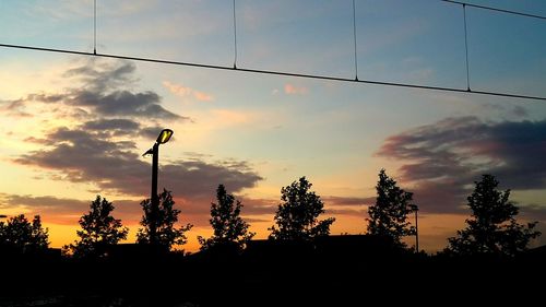 Low angle view of trees against sky at sunset