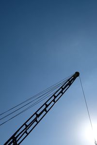 Low angle view of crane against clear blue sky