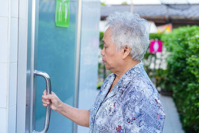 Side view of woman standing against the wall