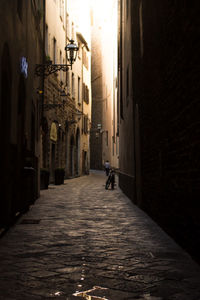 Rear view of woman walking on narrow street