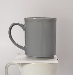Close-up of gray and white coffee cups against white background