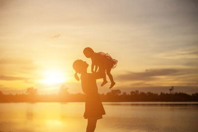 Silhouette woman standing against orange sky during sunset