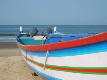 Boat moored on beach against clear sky