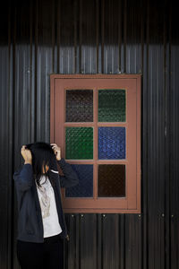 Rear view of woman standing against window
