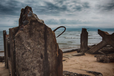 Rusty metal on rock by sea against sky