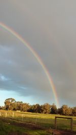 Scenic view of rainbow over field against sky