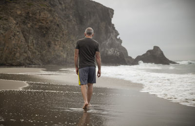 Rear view of adult man walking on beach in cabo de gata nature park, spain, during sunrise