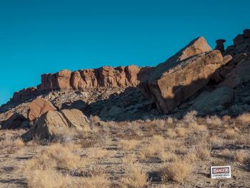 Rock formations on landscape against clear blue sky