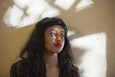 Portrait of young woman against wall