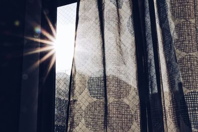 Close-up of sun shining through curtain