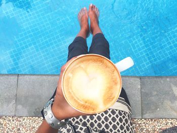 Low section of woman with coffee cup at swimming pool