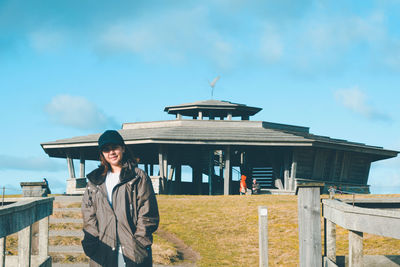 Portrait of young woman standing against sky