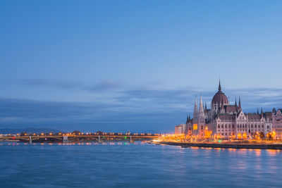 Illuminated buildings in city against sky at dusk