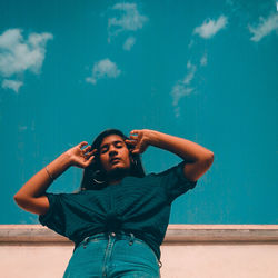 Full length of young man looking away against blue wall