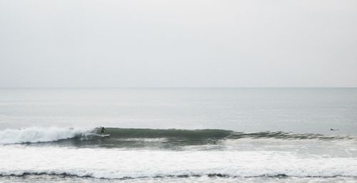 Man surfing in sea against clear sky