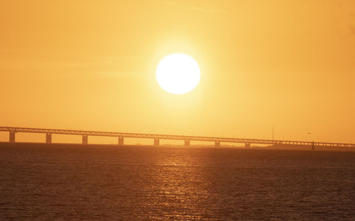 Pier over sea against orange sky