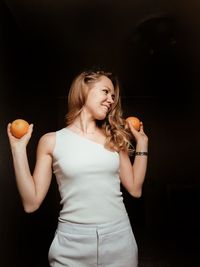 Young woman holding ice cream standing against black background