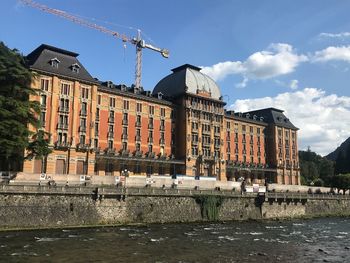 Buildings by river against sky in city