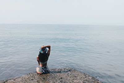 Rear view of man standing at beach against clear sky