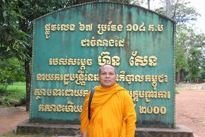Portrait of monk standing against text