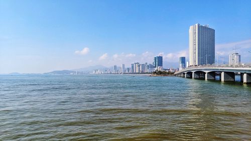 Bridge over sea and buildings against sky