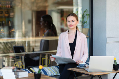 Portrait of young woman using phone while sitting at table