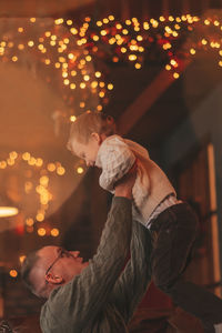Candid authentic happy dad playing with little son fooling around at wooden lodge xmas decorated