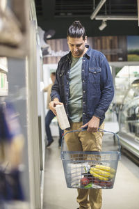 Man putting carton in basket at supermarket