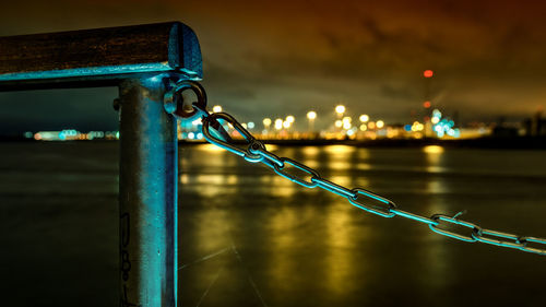 Close-up of metal railing by river at night