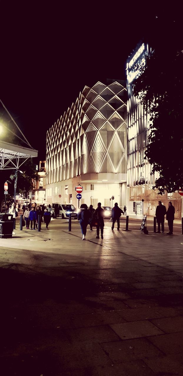 GROUP OF PEOPLE IN ILLUMINATED BUILDING AT NIGHT