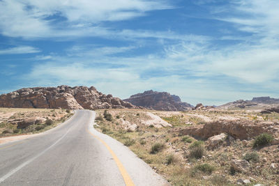 Empty road amidst landscape leading towards rock formations