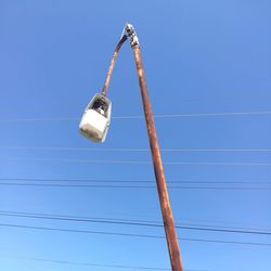 Low angle view of broken street light against clear blue sky