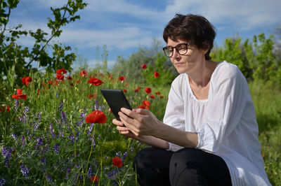 Young woman using mobile phone while sitting in park