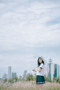 Woman holding umbrella standing against sky