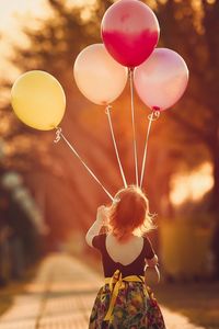 Rear view of girl holding balloons