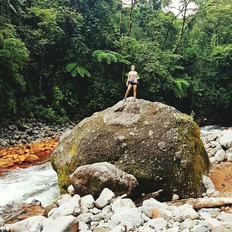 solid, rock, tree, rock - object, plant, full length, standing, one person, nature, beauty in nature, forest, leisure activity, water, day, young women, real people, young adult, casual clothing, lifestyles, outdoors