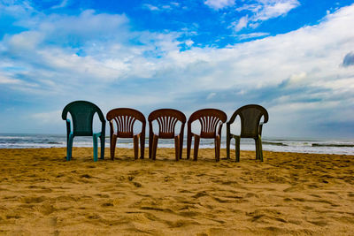 Chairs on beach against sky