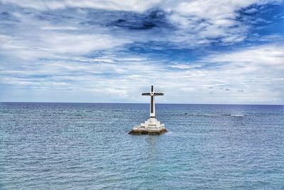 Lighthouse by sea against sky