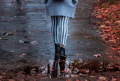 Low section of woman walking on wet road during rainy season