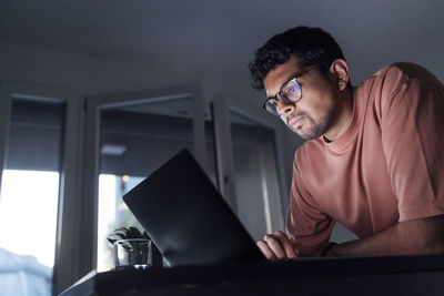 Young man using laptop on table at home