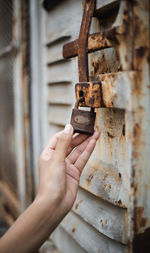 Close-up of hand holding rusty padlock